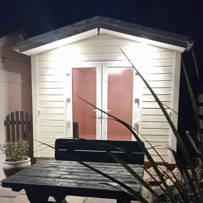 Painted shed at night, custom made in Cornwall by South West Garden Buildings